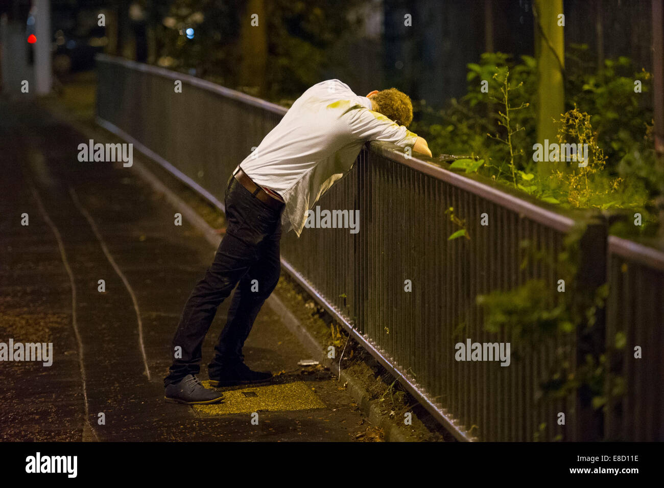 Eine betrunkene Jugend lehnt sich über Geländer nach einer durchzechten Nacht schwere Alkoholexzesse in Cardiff, Wales. Stockfoto