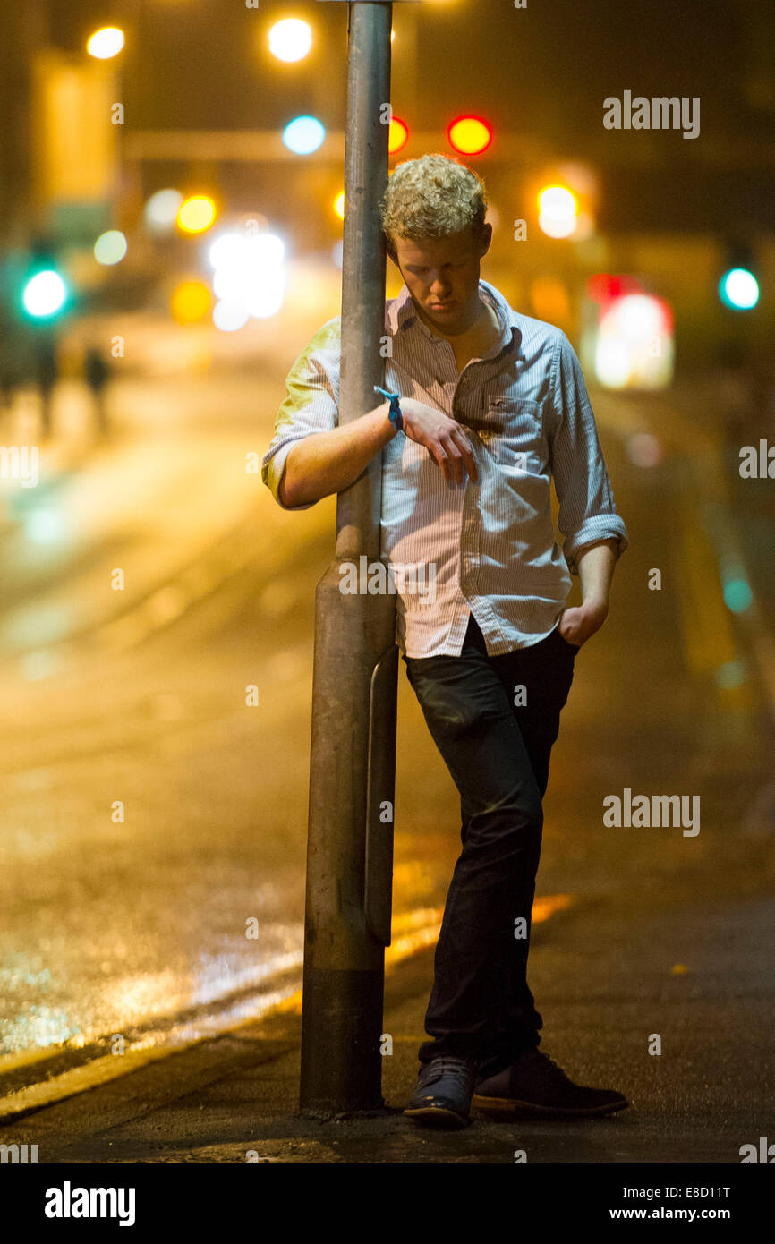 Studentin betrunken lehnt an einem Laternenpfahl nach einer Nacht des Trinkens von Alkohol. Stockfoto