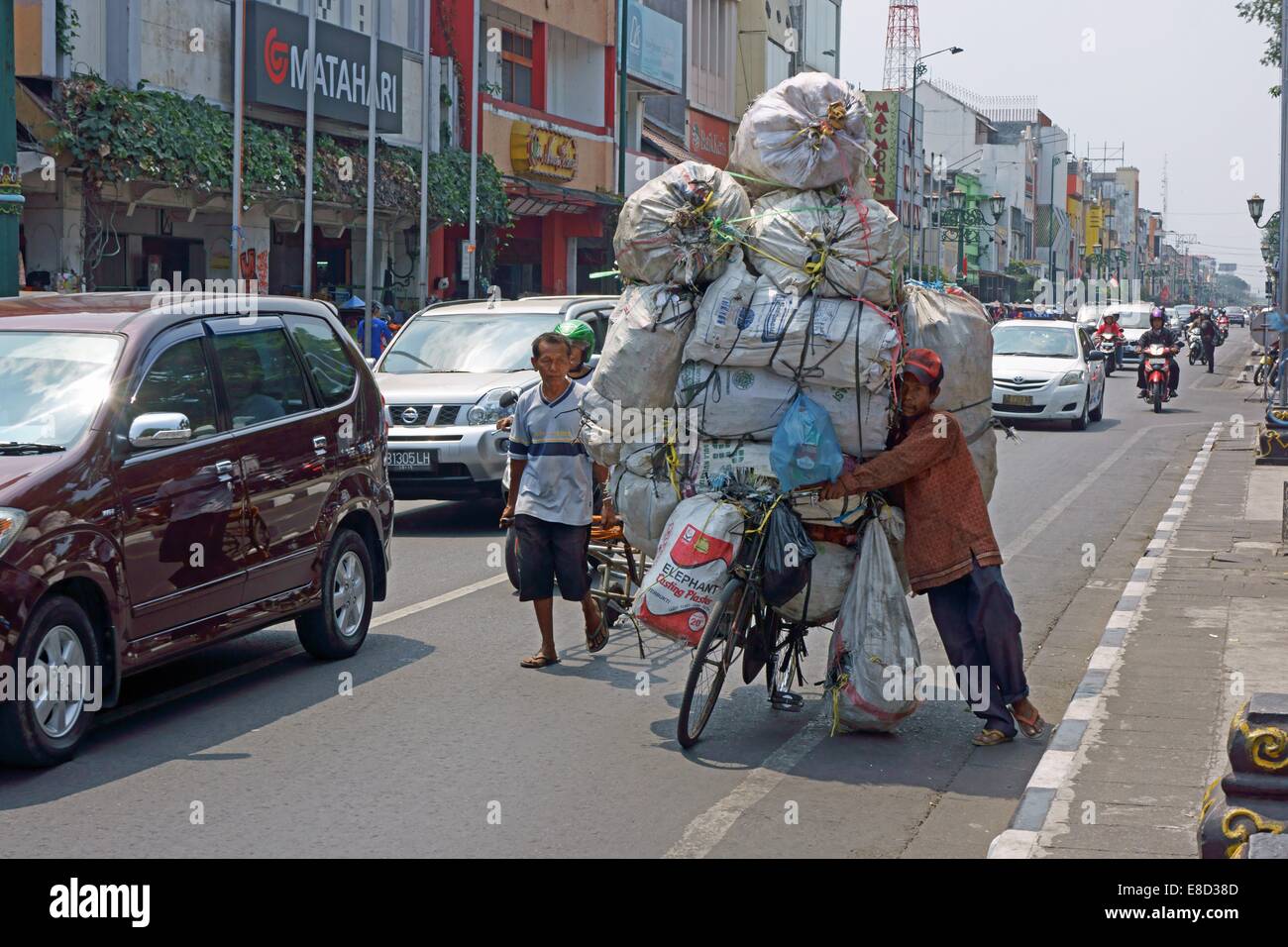 Der Mann unter Kontrolle zu sein scheint Schwierigkeiten das Fahrrad balancieren, als er die Ladung transportiert. Stockfoto