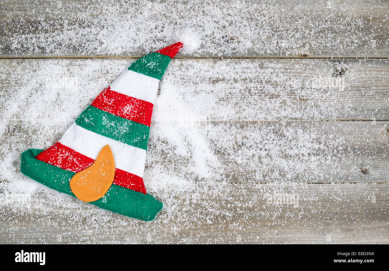 Horizontales Bild von Elf Strumpf Weihnachtsmütze auf urigen Holzbrettern mit Schnee bedeckt Stockfoto