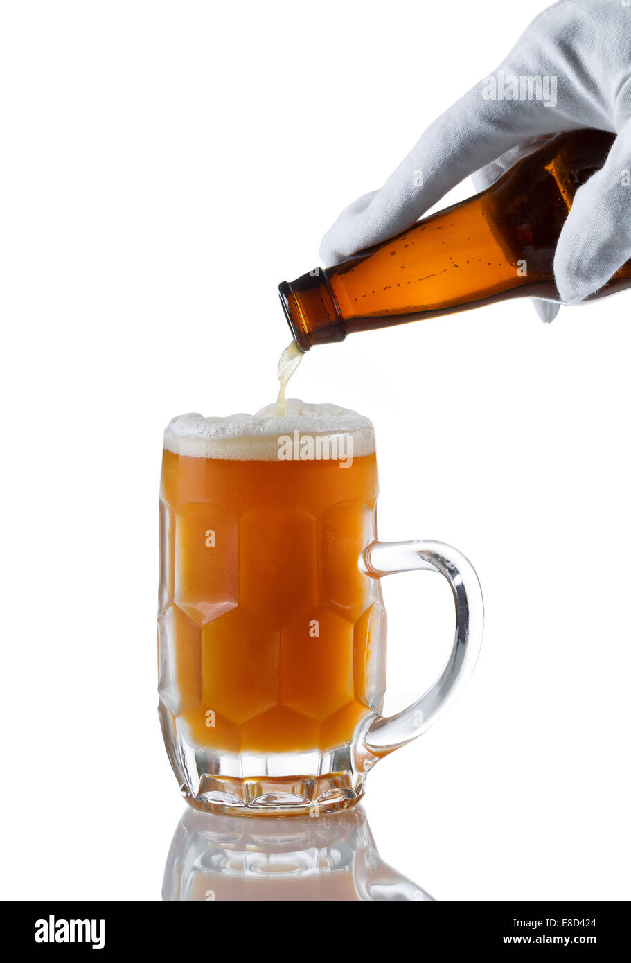 Vertikales Bild der behandschuhten Hand Gießen bernsteinfarben Bier in Glas Stein auf weiß mit Reflexion Stockfoto