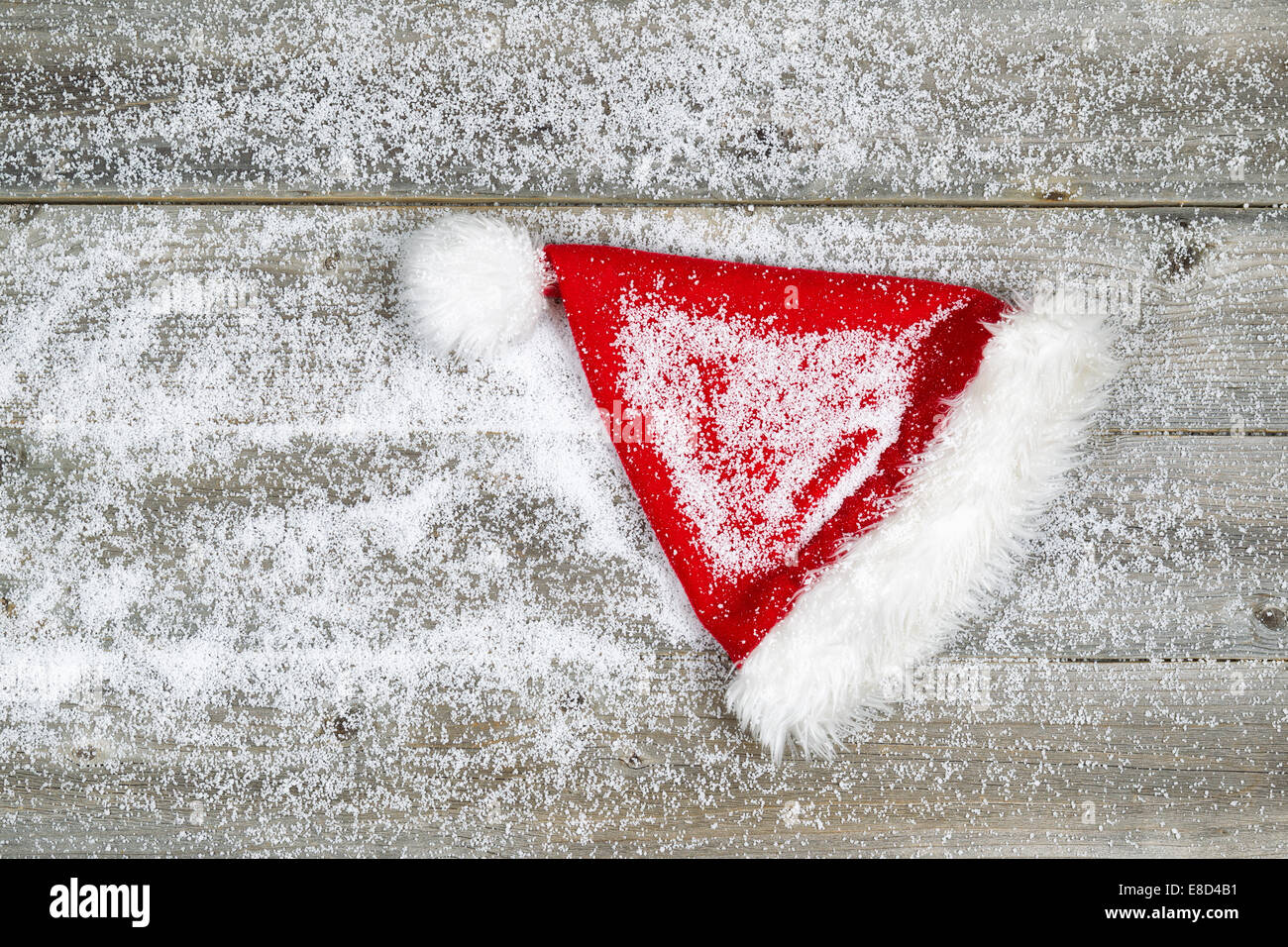 Horizontales Bild von Weihnachten Santa Hut, mit Schnee bedeckt, auf urigen Holzbrettern Stockfoto