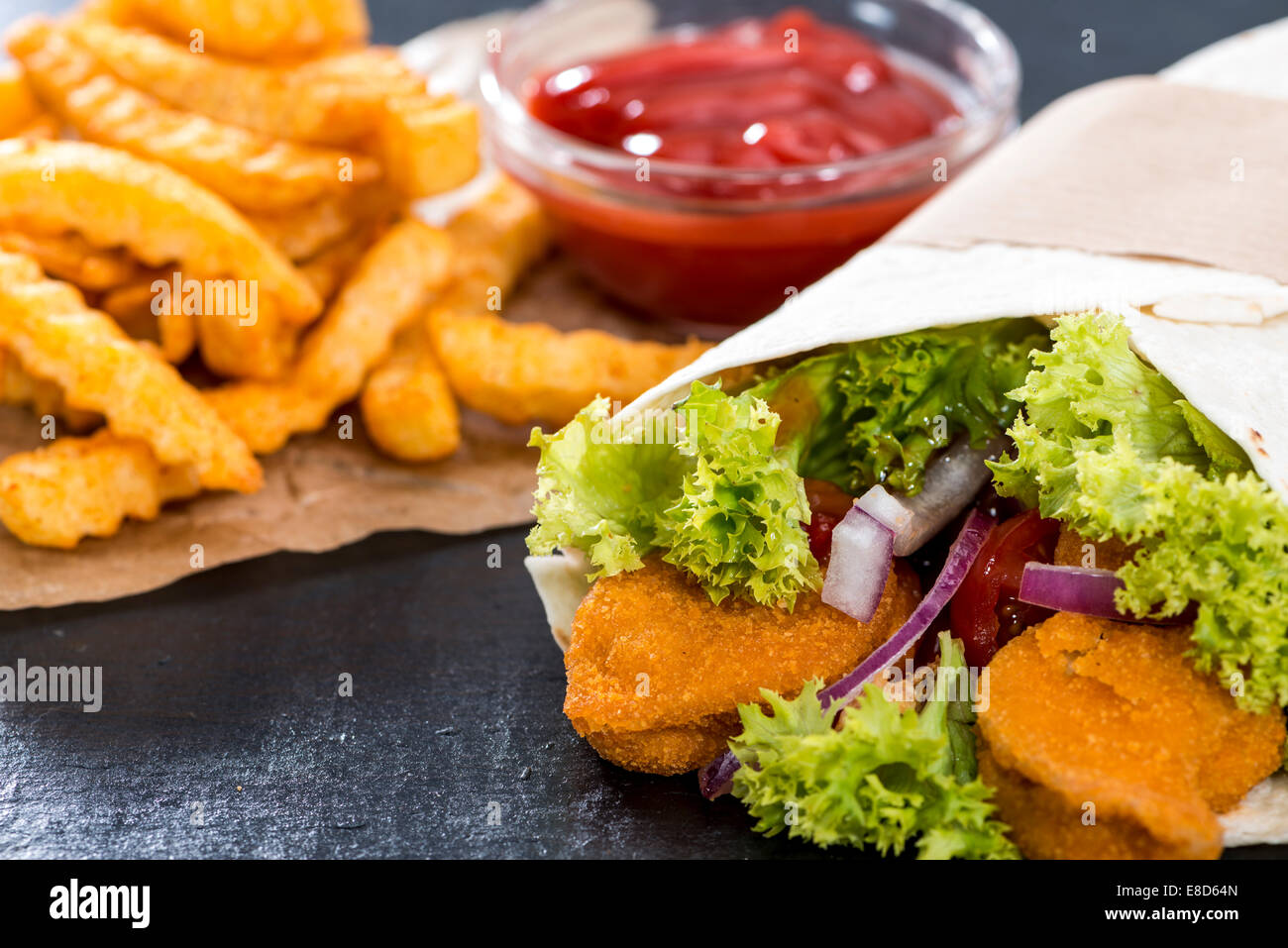 Chicken Wrap (Nahaufnahme) mit knusprig gebratene Hähnchen und Pommes frites Stockfoto