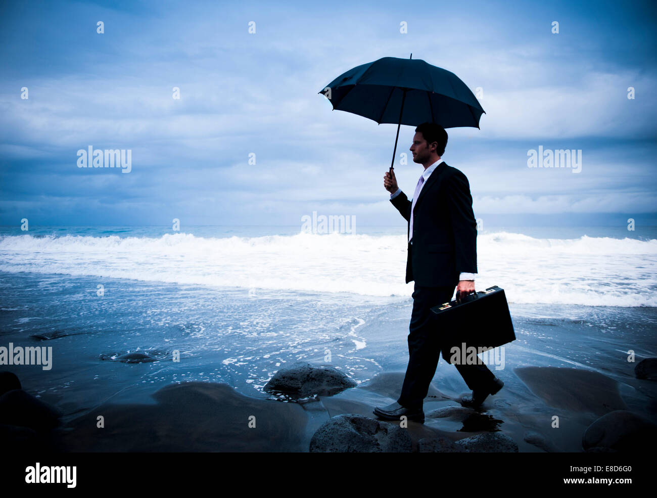 Einsamer Geschäftsmann zu Fuß am Strand Stockfoto