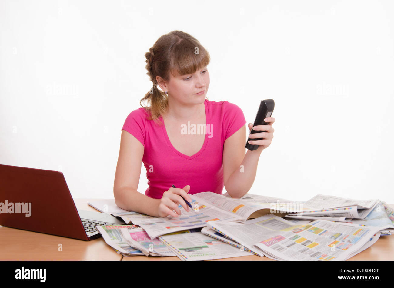 Ein junges Mädchen sitzt an einem Tisch mit einem Haufen von Zeitungen, Lexika und einen laptop Stockfoto