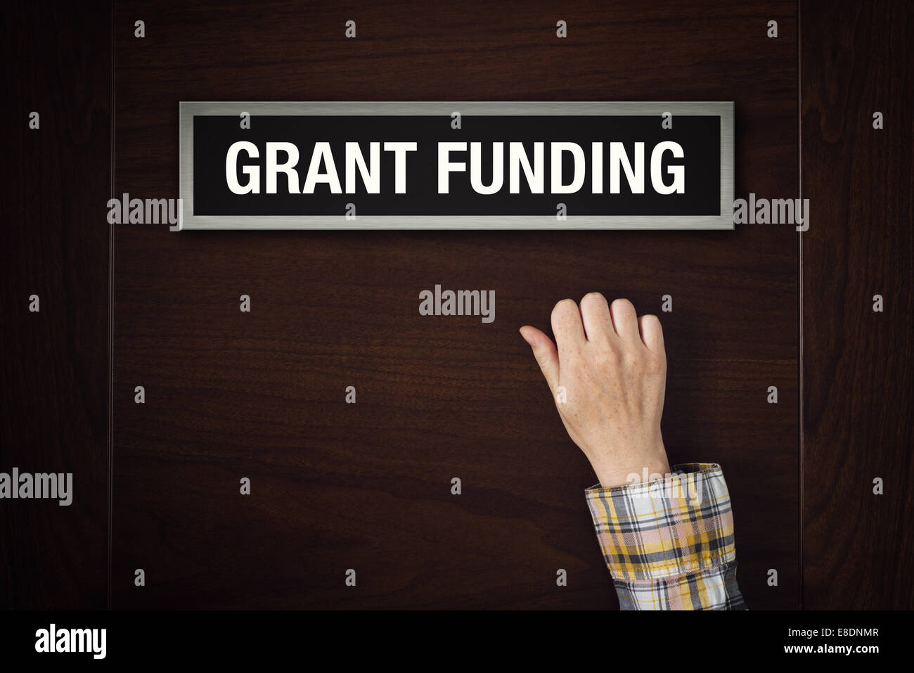 Weibliche Hand klopft an Grant Funding Tür, Konzeptbild. Stockfoto