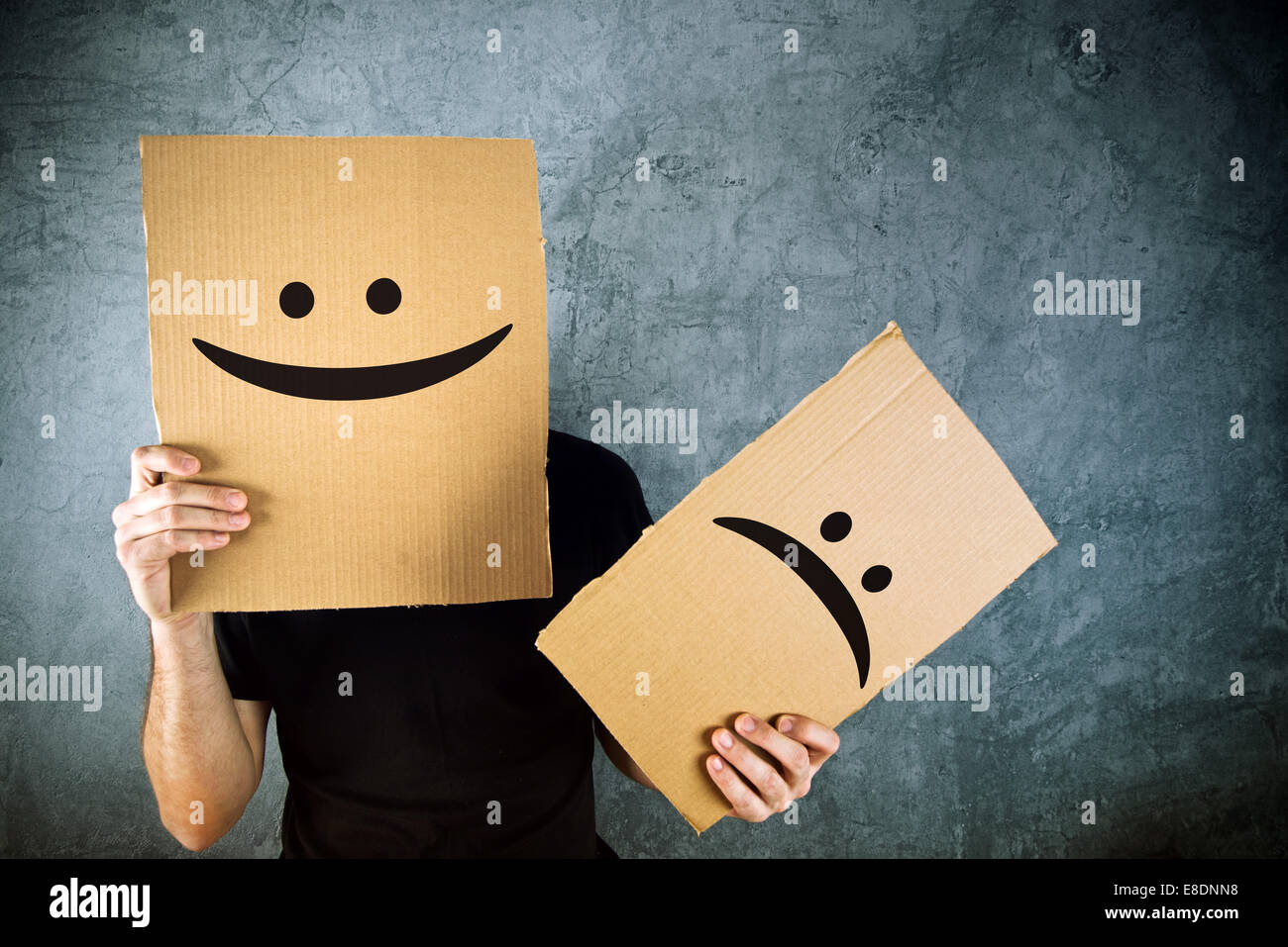 Mann hält Pappe mit glücklichen Smiley Gesicht bedruckt. Glück und Freude-Konzept. Stockfoto
