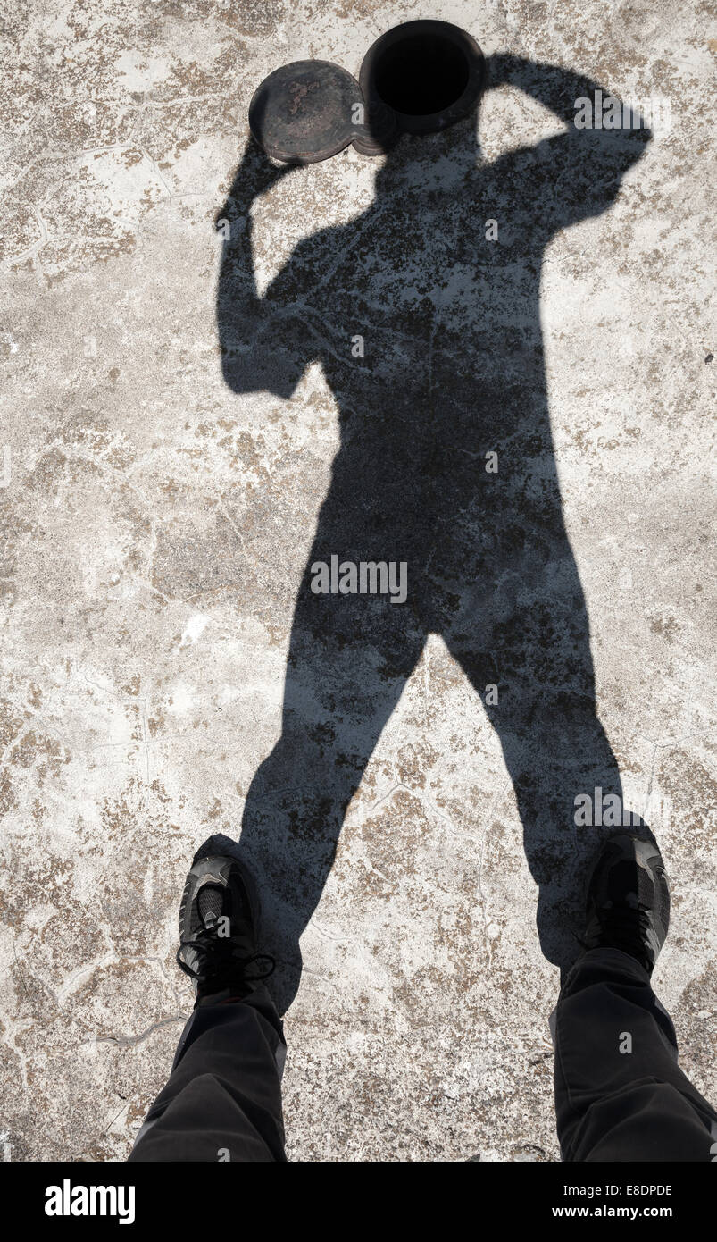 Schatten eines Mannes öffnet kleine Luke im Kopf auf alten Betonboden Stockfoto