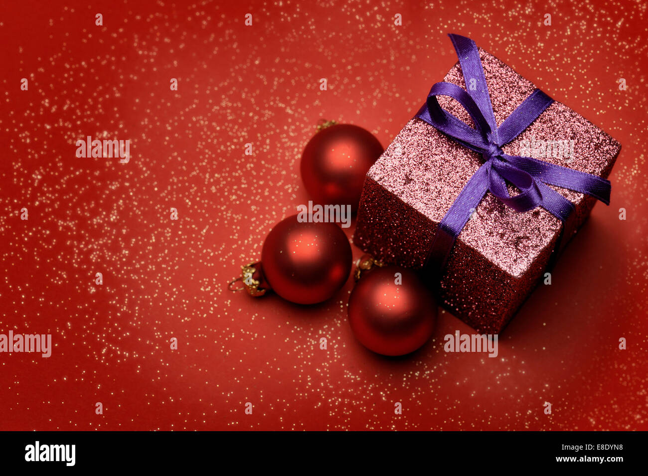 bunte Geschenkbox mit roten Weihnachtskugeln auf rotem Grund Stockfoto