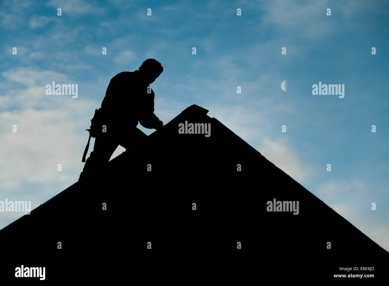 Auftragnehmer im Silhouette arbeiten auf einem Dach mit blauen Himmel im Hintergrund Stockfoto