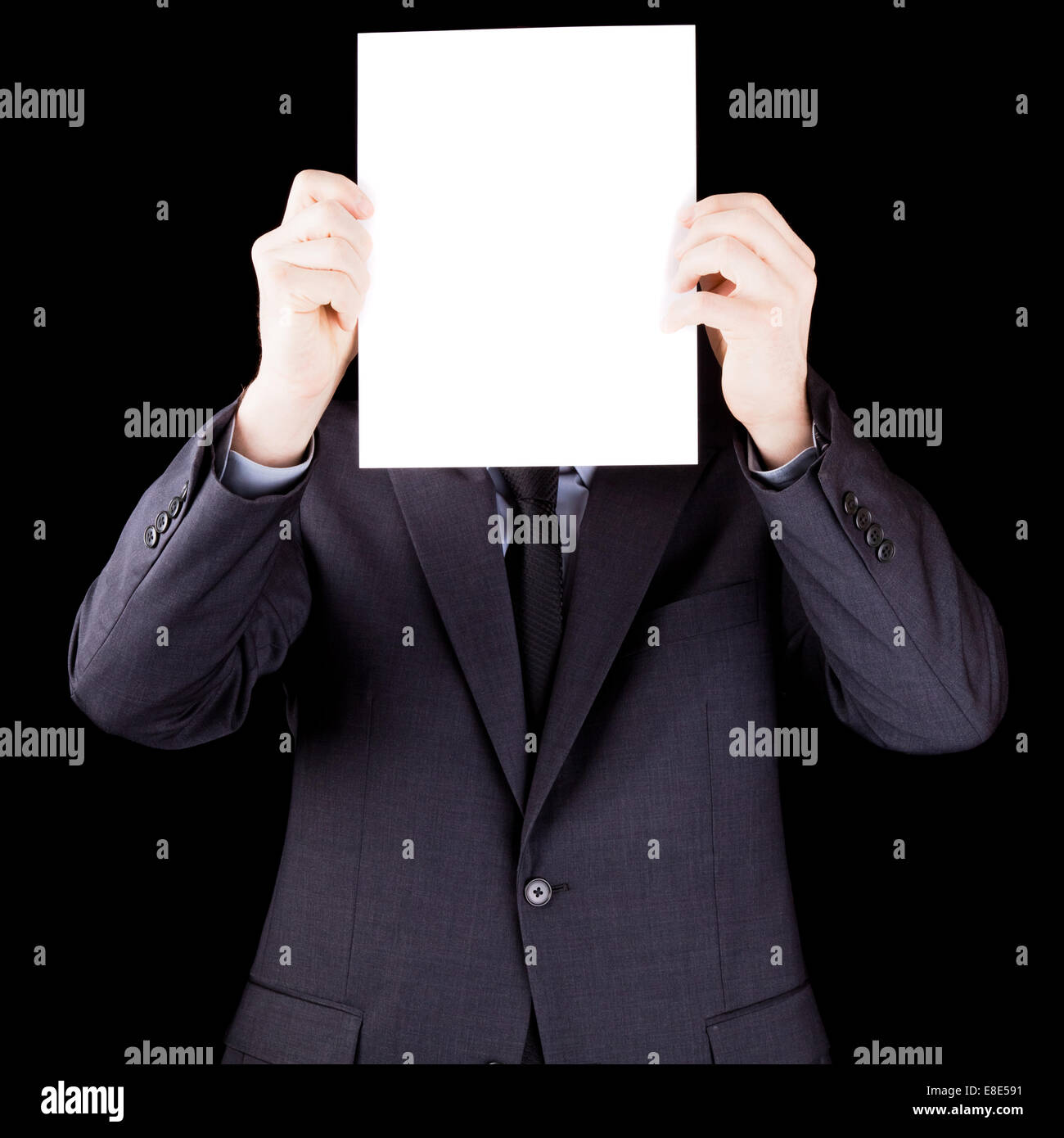 Geschäftsmann mit einem Blatt Papier vor seinem Gesicht auf schwarzem Hintergrund isoliert Stockfoto