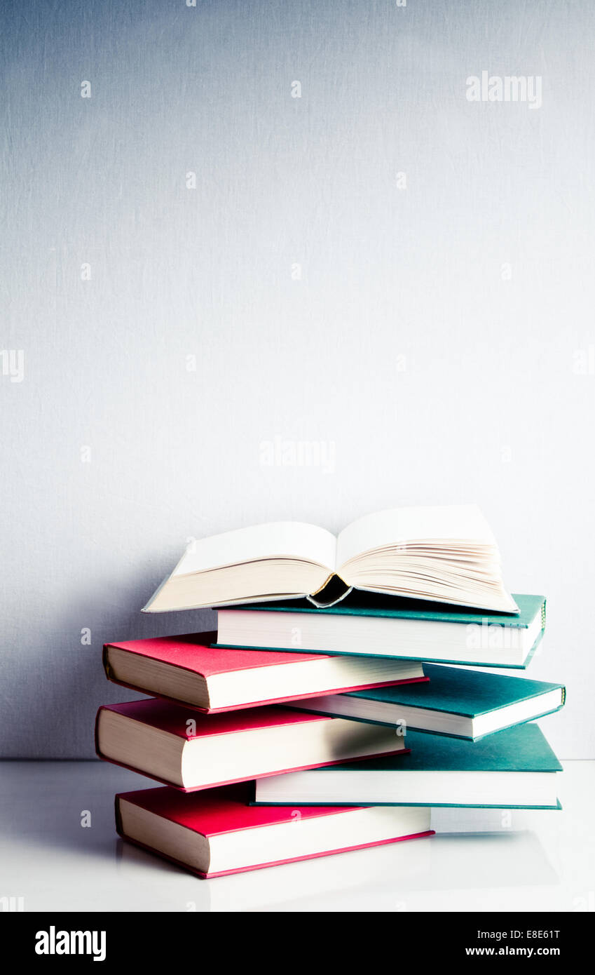 Leere offenes Buch auf eine grüne und rote Stapel von Büchern im Gleichgewicht Stockfoto