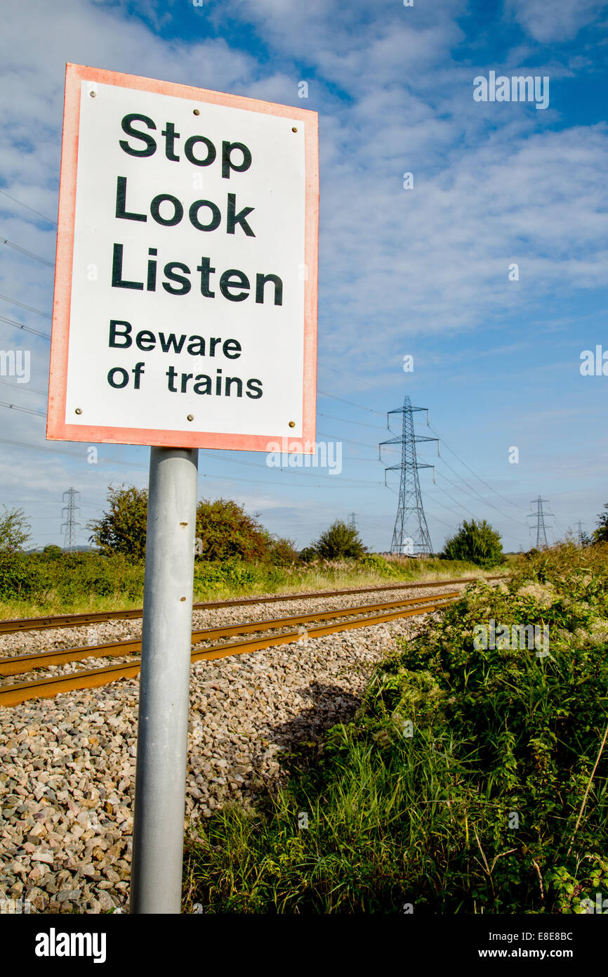 Fuß Überquerung einer belebten Eisenbahnstrecke mit einem Warnhinweis zu stoppen sehen und hören für Züge Stockfoto
