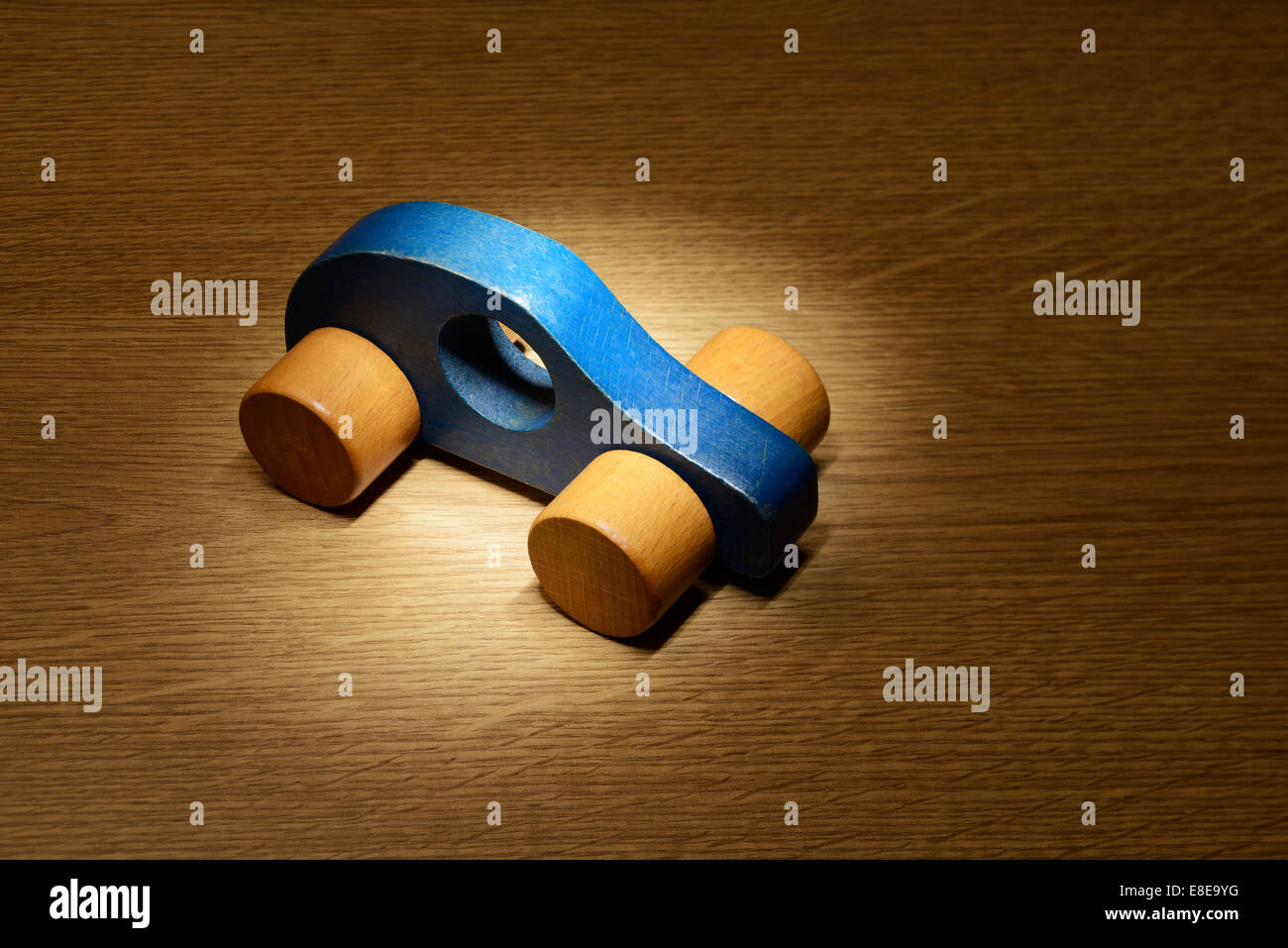 Scheinwerfer auf ein blaues Spielzeugauto aus Holz Stockfoto
