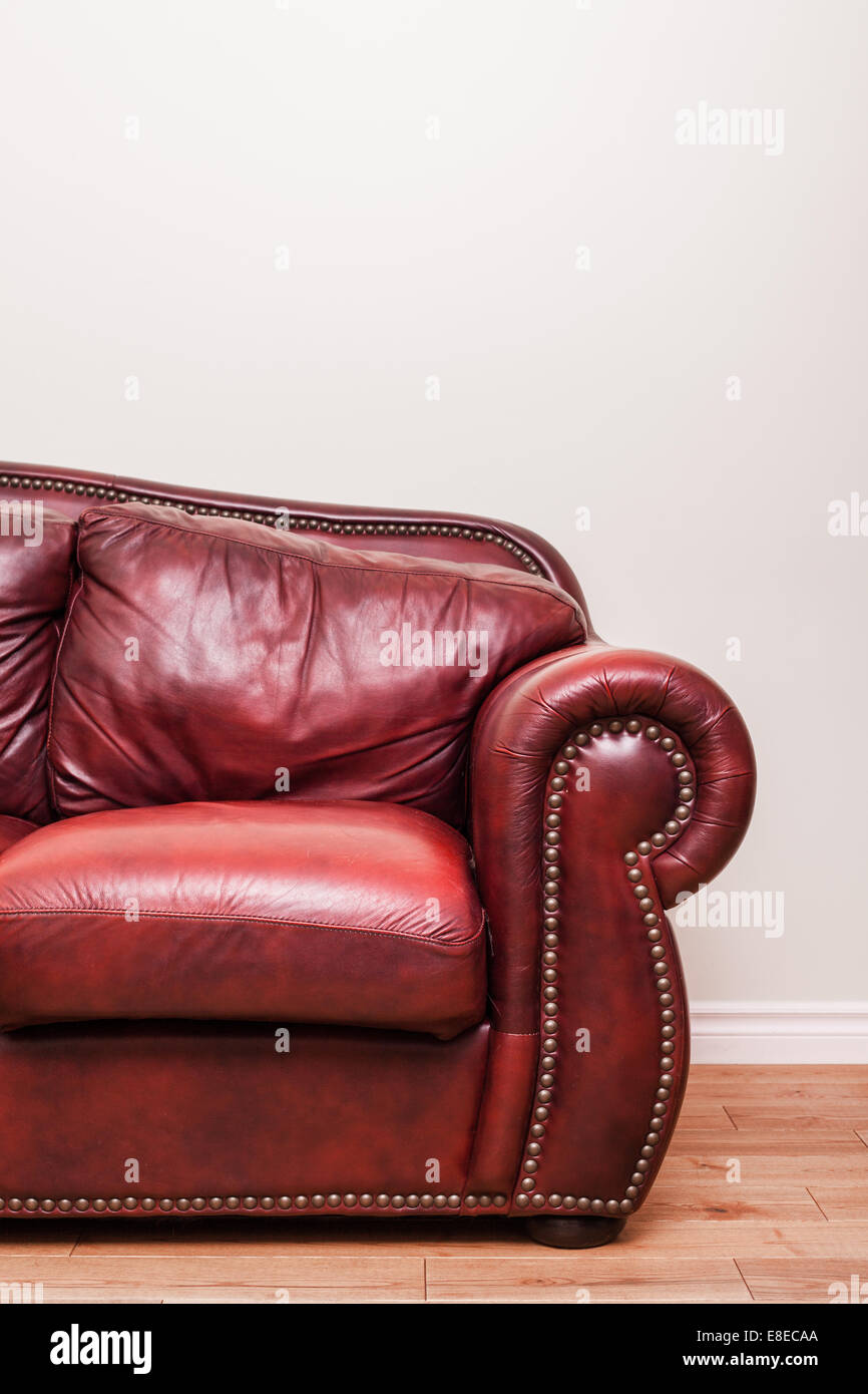 Luxuriöse rot Leder Couch Detail vor einer leeren Wand Anzeige Text, Logos, Bilder usw.. Stockfoto
