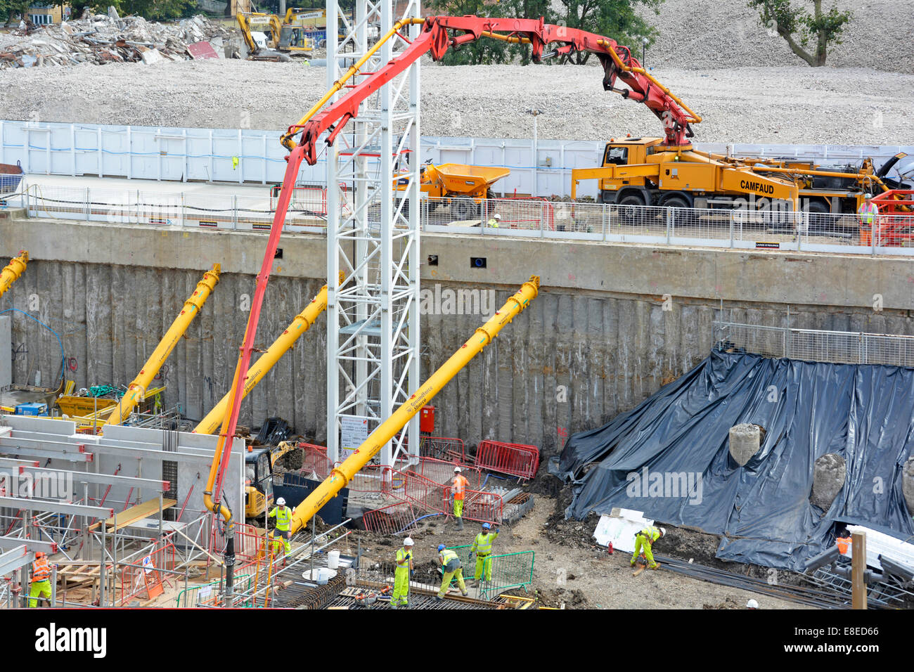 Pumpen von Beton zu Untergeschossfundament um gelbe hydraulische Stützstreben zu stapeln Stützwand Baustelle London England UK Stockfoto
