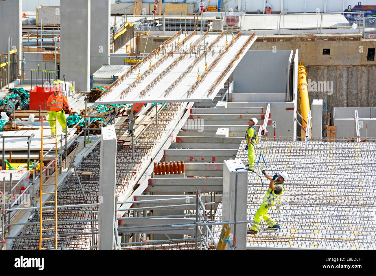 Baustelle Arbeiten im Gange Arbeiter in hoher Sichtbarkeit Jacke & Hut Arbeiter & Kran Positionierung Betonboden Panel London UK Stockfoto