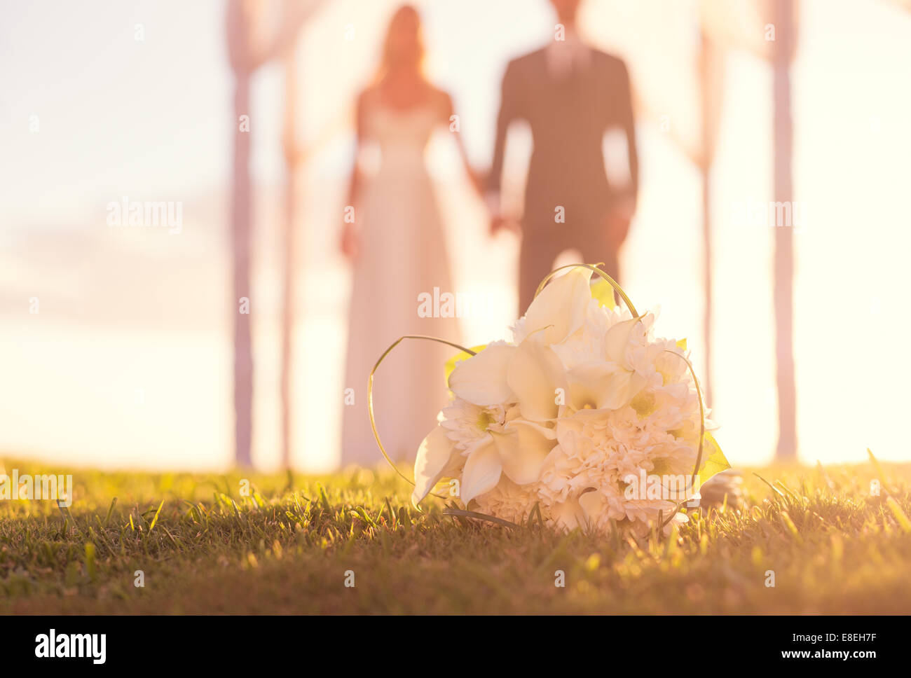 Nahaufnahme der Brautstrauß. Blumen im Mittelpunkt. Braut und Bräutigam im Hintergrund. Stockfoto