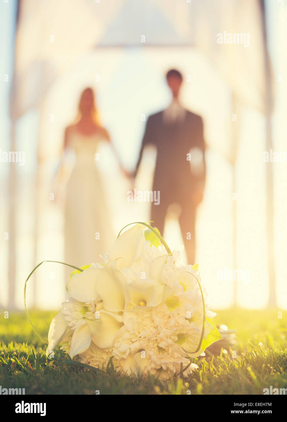 Nahaufnahme der Brautstrauß. Blumen im Mittelpunkt. Braut und Bräutigam im Hintergrund. Stockfoto