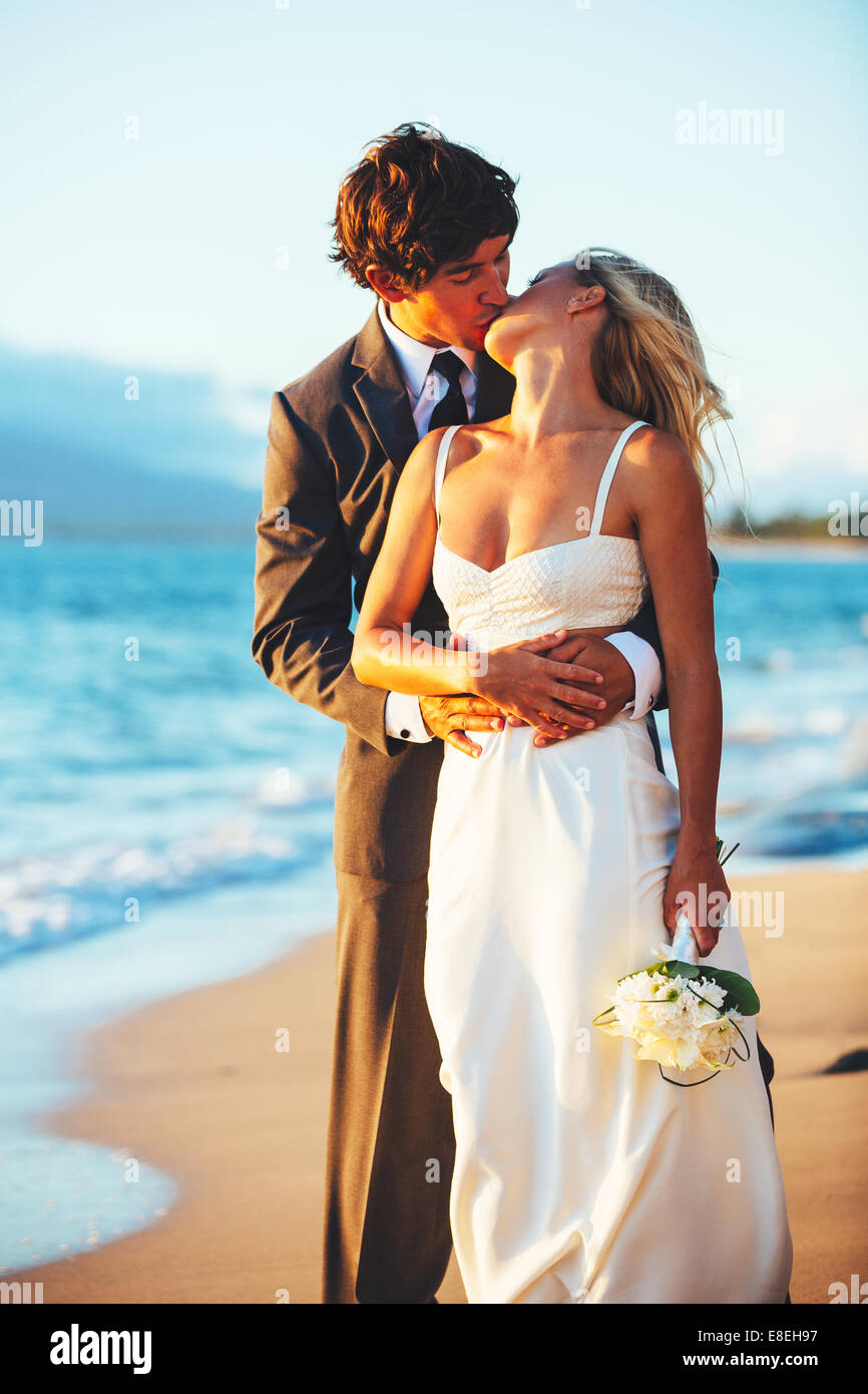 Romantische Hochzeit paar küssen am Strand bei Sonnenuntergang Stockfoto