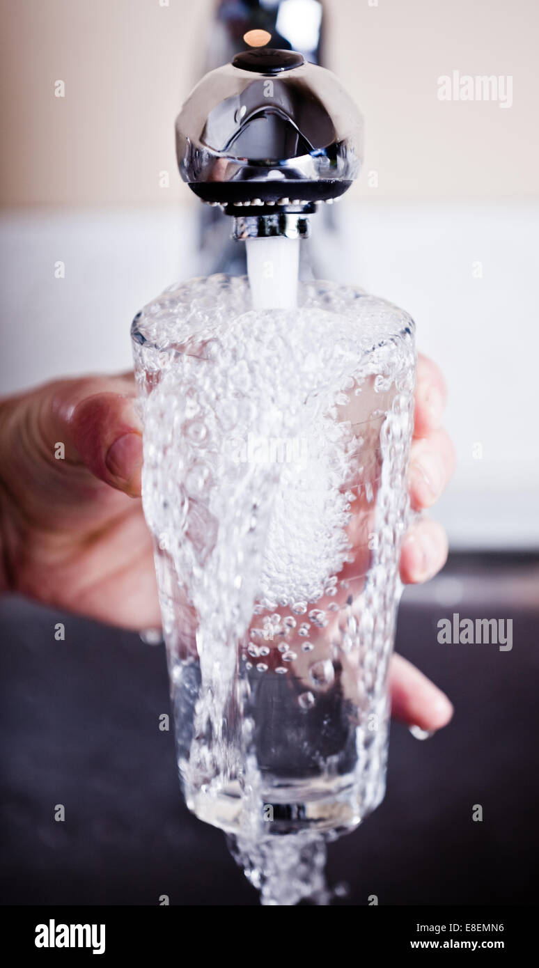 Durstige Mann eine überquellende Glas Wasser füllen Stockfoto