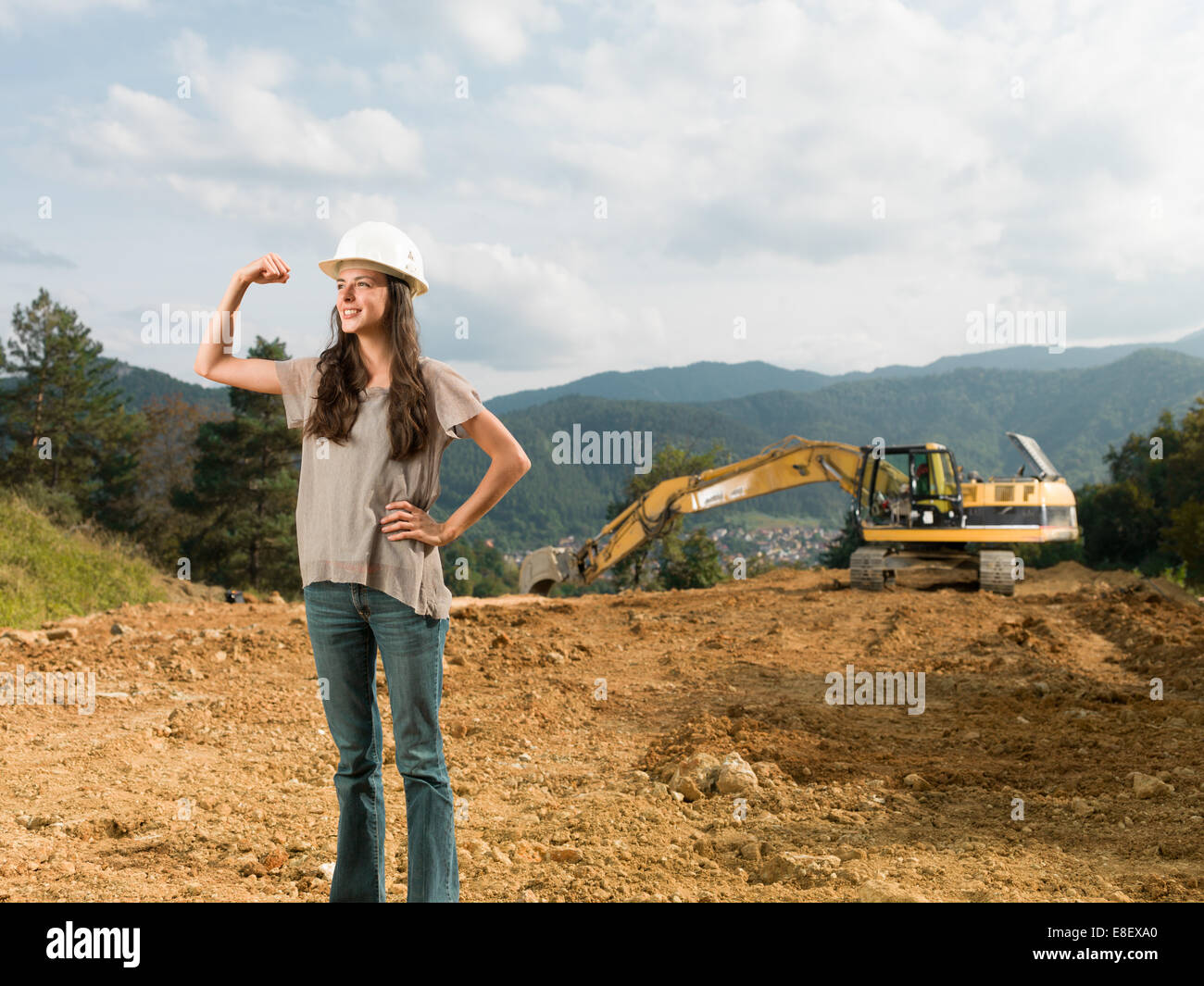 Junge glücklich kaukasischen Ingenieurin zeigt ihre Stärke und Muskeln auf Baustelle Stockfoto