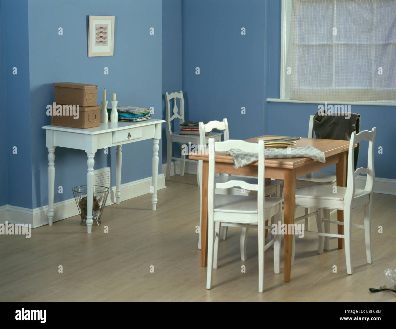 Weiss lackiert Stühle an einfache Kiefer Tisch im Speisesaal der blauen Wirtschaft weißen Konsole Tisch mit Holzboden Stockfoto