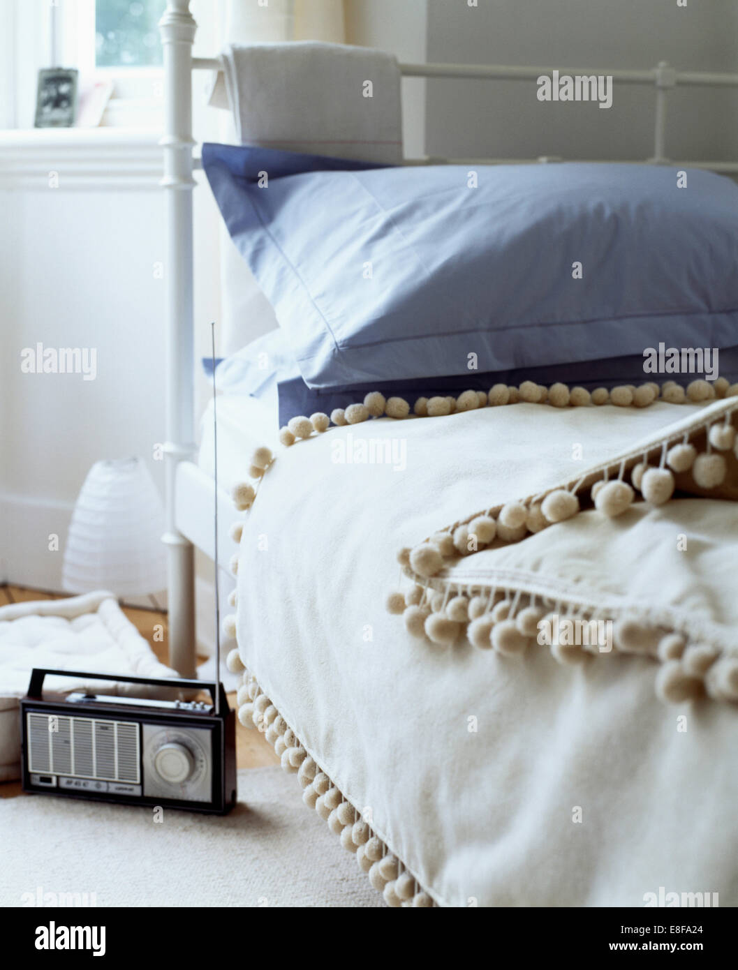 Radio am Boden neben Schmiedeeisen-Bett mit blauen Kissen und Bettdecke  weiße Bommel getrimmt Stockfotografie - Alamy