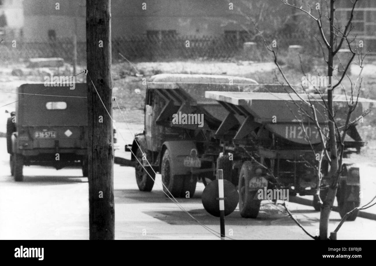 Ein LKW-LKW mit Anhänger ist wieder ein Militärjeep gespeist nach zwei Ost-Berliner Arbeiter es für eine Flucht über den westlichen Teil der Stadt am 9. April 1962 verwendet. Sie rammte die Grenzmauer und entkam durch das entstandene Loch. Vom 13. August 1961, der Tag der Gebäude der Berliner Mauer waren Deutschland und der DDR bis zum Fall der Berliner Mauer am 9. November 1989 durch einen Eisernen Vorhang zwischen Ost und West aufgeteilt. Stockfoto