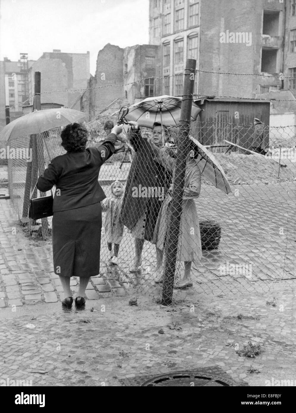 Eine Frau aus West-Berlin übergibt etwas über den Draht, der in der Zwischenzeit die beiden Teile der Stadt teilt, zu einer Familie in Ost-Berlin am 16. August 1961. Stockfoto