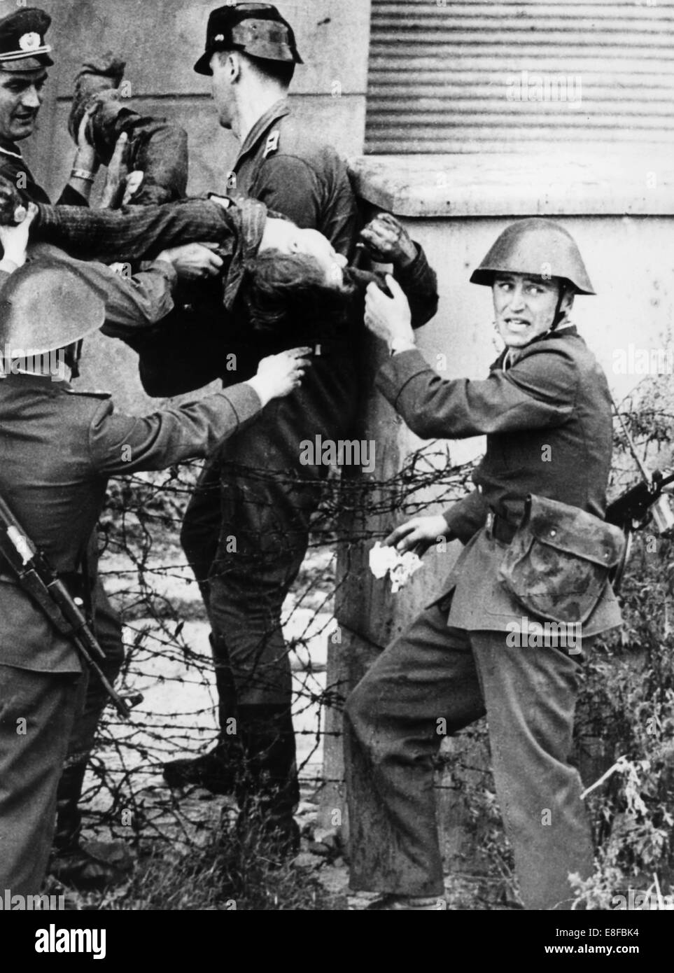 Der Körper der 18 Jahre alte Ost-Berliner Maurer Peter Fechter wird von DDR-Grenzsoldaten weggetragen. Fechter wurde bei seinem Fluchtversuch nach West-Berlin am 17. August 1962 von Ost-Berliner Grenzsoldaten an der Berliner Mauer erschossen. Der verletzte junge Mann lag fast eine Stunde an der Wand, bevor er starb und wurde evakuiert. Vom 13. August 1961, der Tag der Gebäude der Berliner Mauer waren Deutschland und der DDR bis zum Fall der Berliner Mauer am 9. November 1989 durch einen Eisernen Vorhang zwischen Ost und West aufgeteilt. Stockfoto
