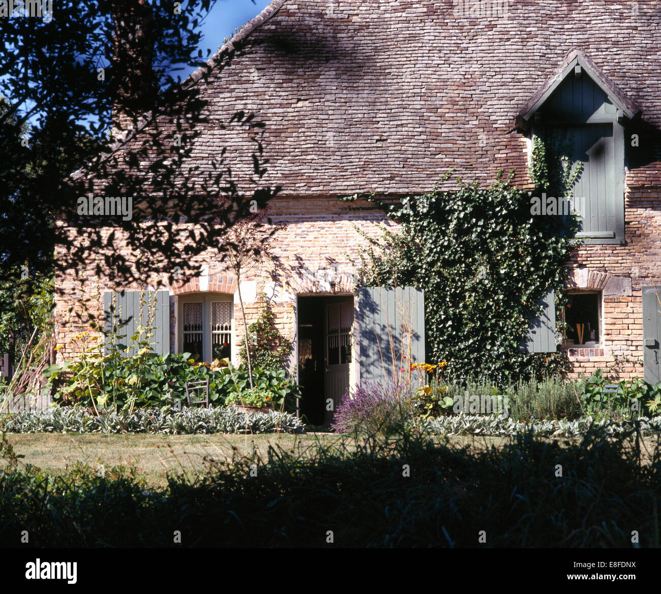 Niedrig-roofed französischen Bauernhaus mit grünen Fensterläden an Fenstern und Türen Stockfoto