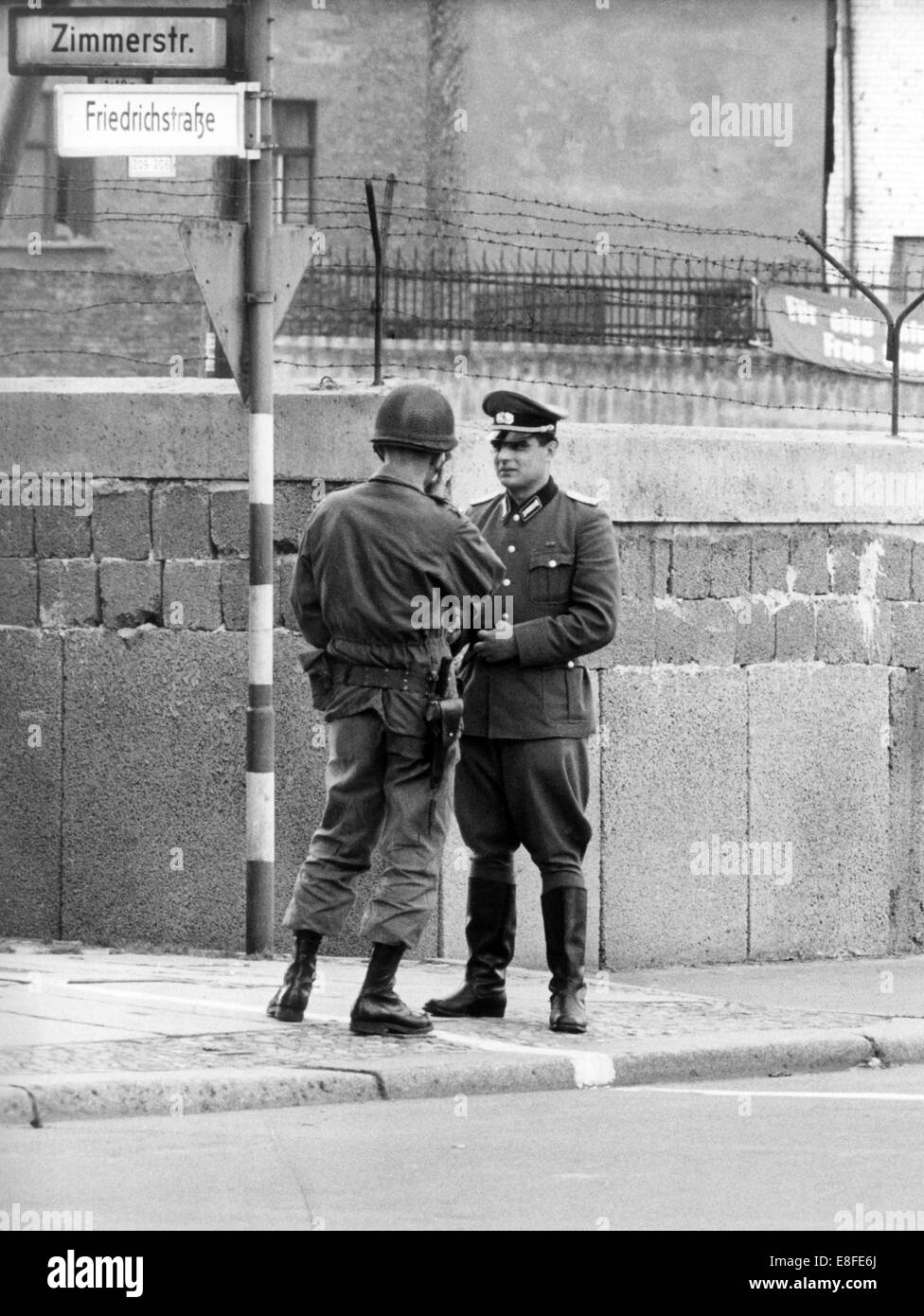 Ein Soldat der US Army (l) und ein Offizier der Volkspolizei in der GDR (r) stehend von Angesicht zu Angesicht, nur getrennt durch eine Grenzlinie am Kontrollpunkt Friedrichstraße am 17. Oktober 1961. Vom 13. August 1961, der Tag der Errichtung der Mauer, waren bis zum Fall der Berliner Mauer am 9. November 1989 der Bundesrepublik und der DDR durch den "Eisernen Vorhang" zwischen Ost und West getrennt. Stockfoto