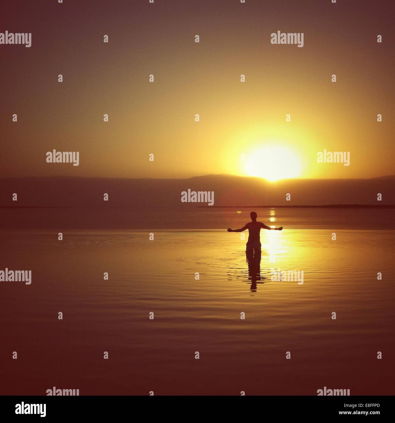 Silhouette eines Mannes stehend im Toten Meer bei Sonnenuntergang, Israel Stockfoto