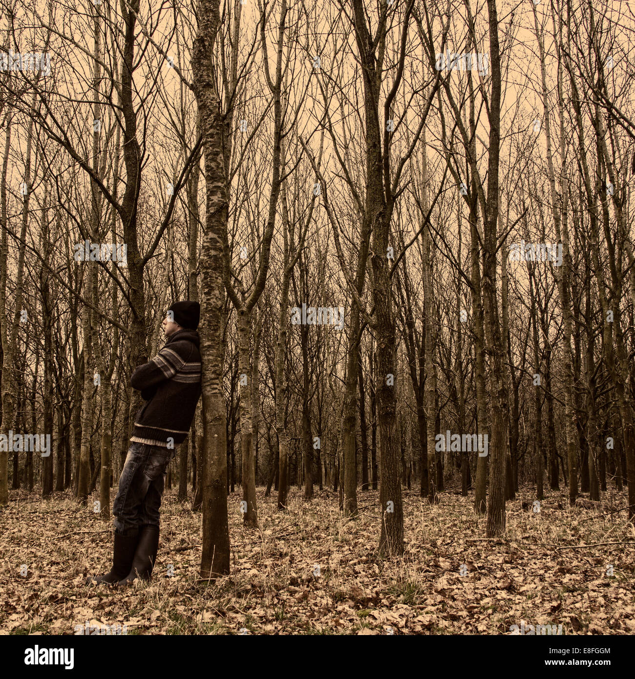 Mann im Wald an einen Baum gelehnt stehen Stockfoto