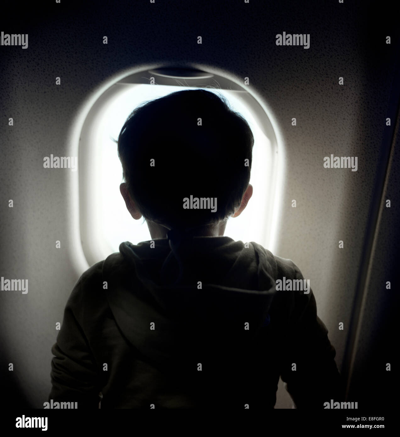 Junge Blick durch Fenster in Flugzeug Stockfoto