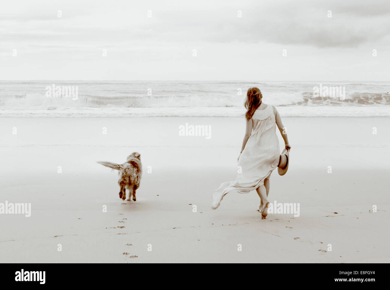 Frau, die mit ihrem Hund am Strand läuft, Südafrika Stockfoto