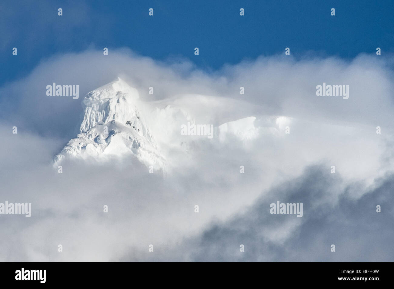 Berggipfel durch Wolken Stockfoto