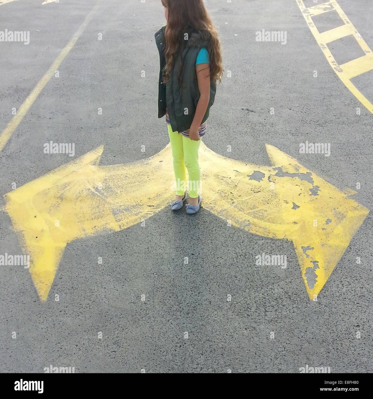 Mädchen auf der Straße zwischen Pfeil Straßenmarkierungen, Australien Stockfoto