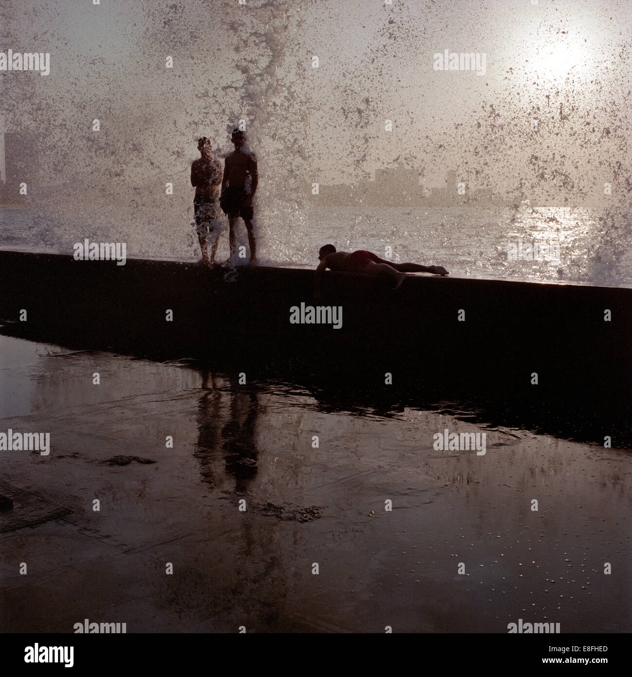 Drei Personen auf einem Steg am Meer, Havanna, Kuba Stockfoto