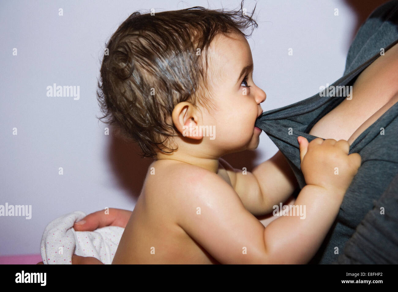 Babymädchen beißen und ziehen Mutter t-shirt Stockfoto