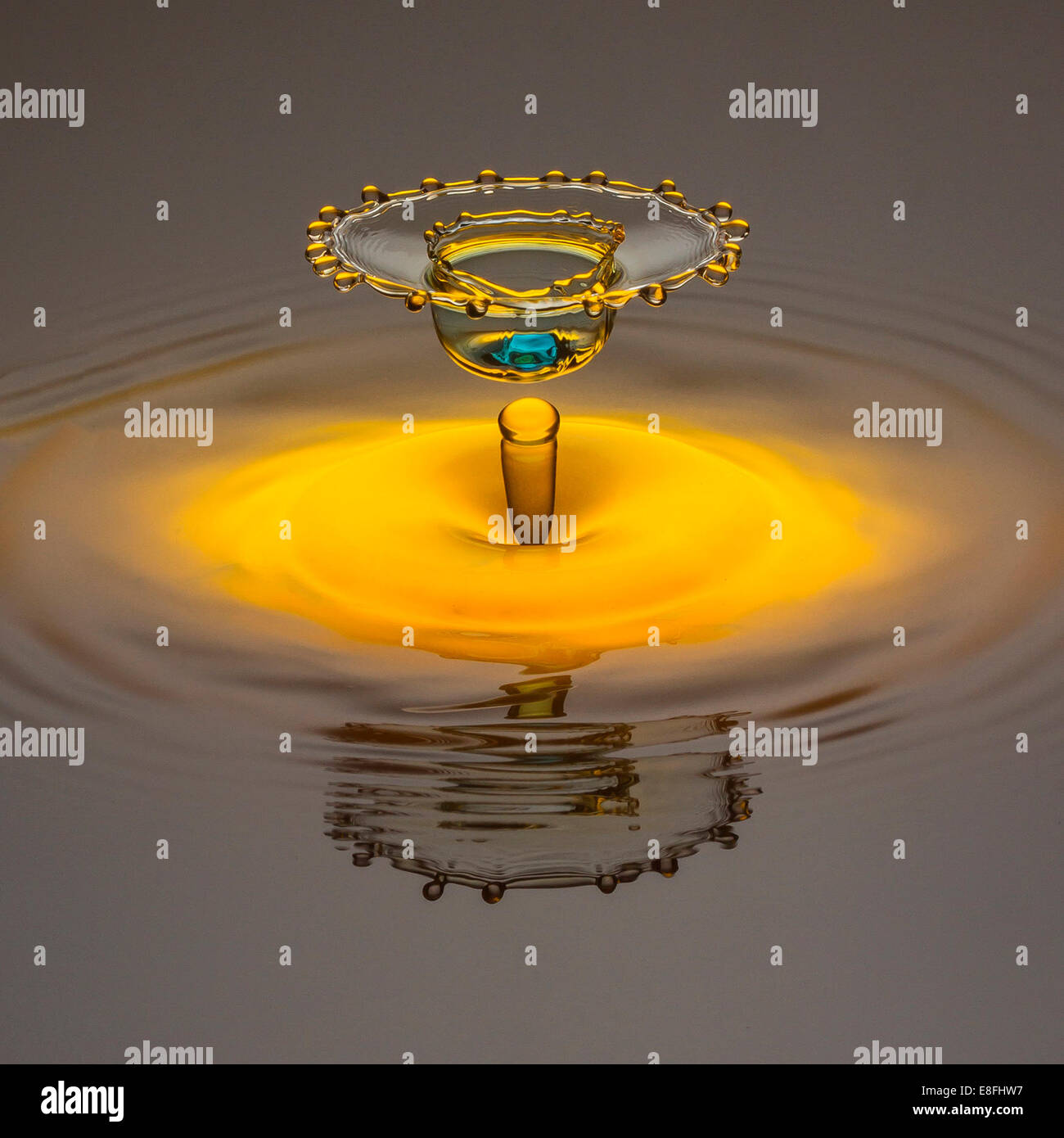 Gelbes Wasser Tropfen bilden Krone mit leichten blauen Punkt in Mitte Stockfoto