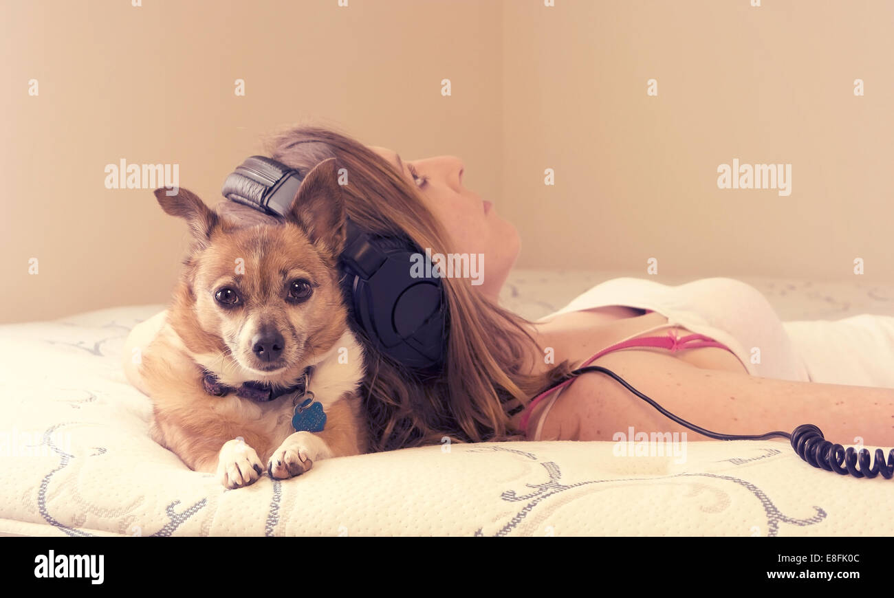 Junge Frau, die mit ihrem Hund auf dem Bett liegt Stockfoto