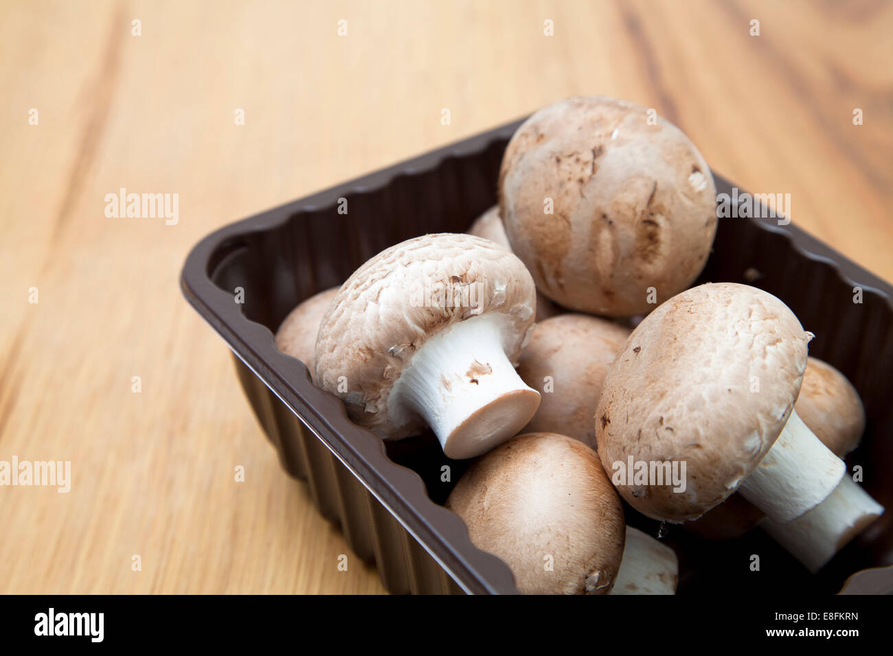 Nahaufnahme eines Punnets von braunen Pilzen auf einem Tisch Stockfoto