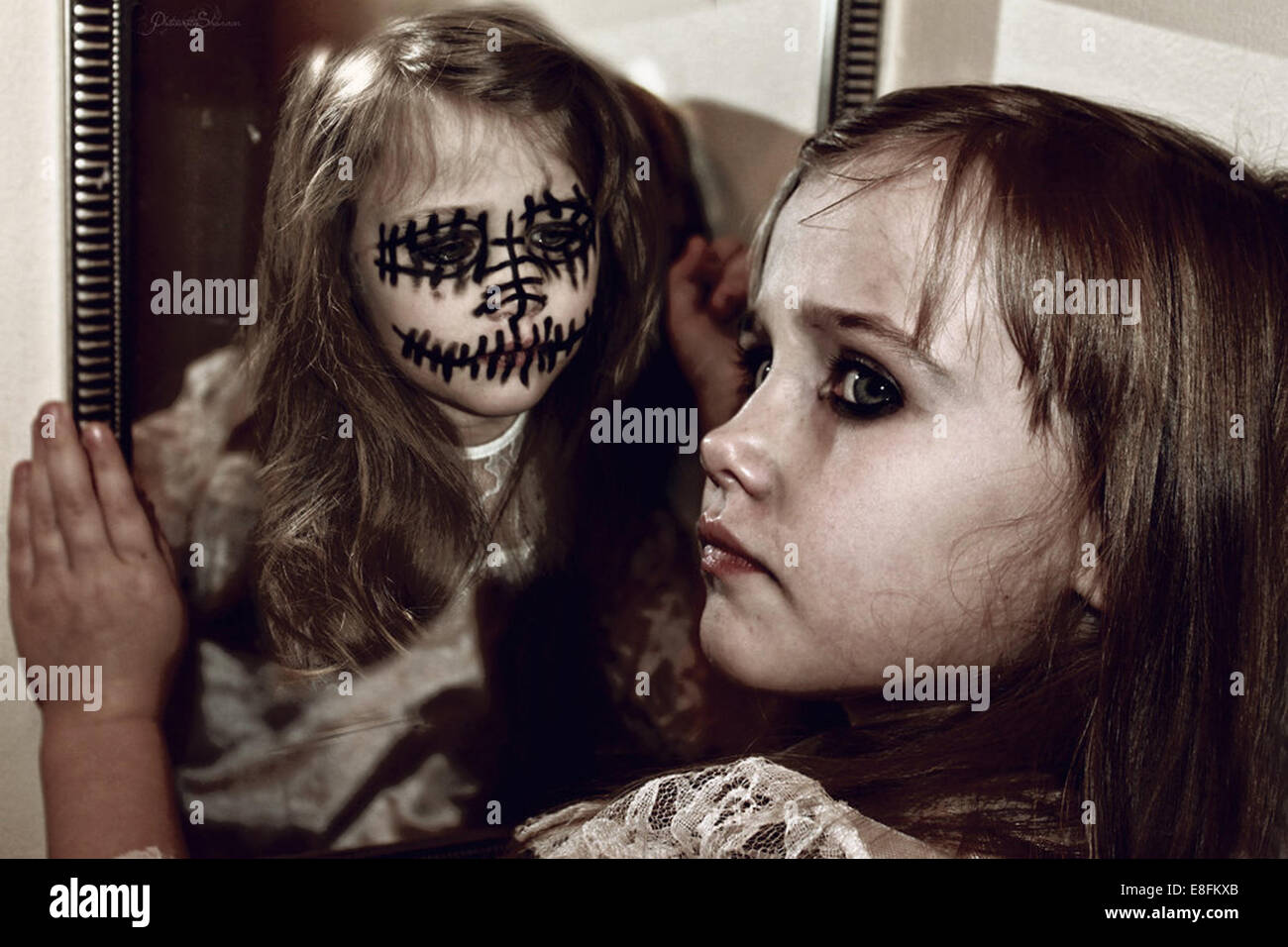 Mädchen sitzt auf dem Boden mit einem Spiegelbild ihres Alter Ego im Spiegel Stockfoto