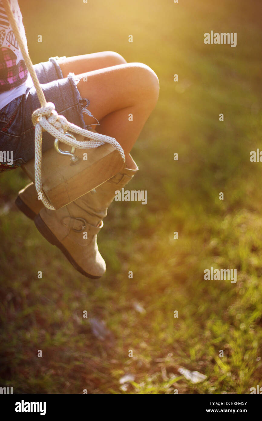 Nahaufnahme der Beine eines Mädchens, das auf einer Seilschaukel im Garten, Mississippi, USA, sitzt Stockfoto