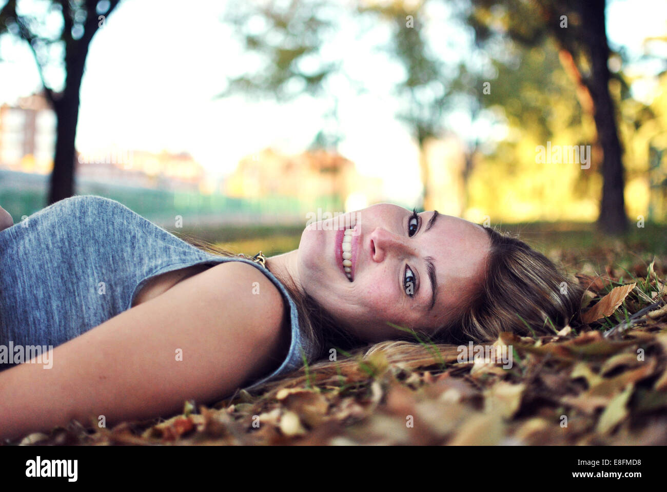 Porträt der lächelnde junge Frau liegend auf Blätter im Herbst Stockfoto