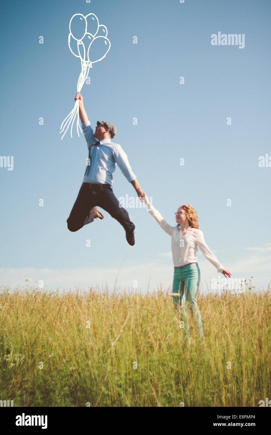 Frau, die auf einer Wiese steht und ihre Freunde in der Hand hält, während er mit Luftballons in Nashville, Tennessee, USA, fortschwimmt Stockfoto