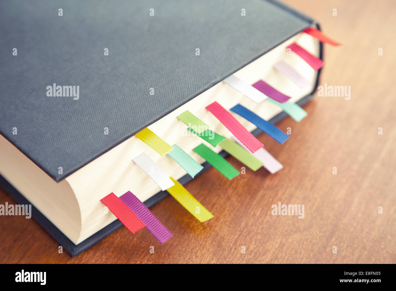 Nahaufnahme eines Hardback-Buches auf einem Tisch mit mehrfarbigen Lesezeichen Stockfoto
