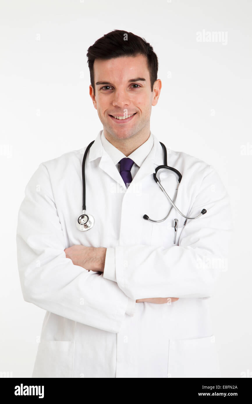 Porträt eines lächelnden männlichen Arztes in einem Labormantel mit gefalteten Armen Stockfoto